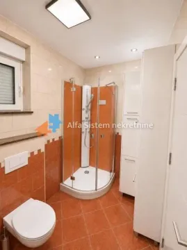 Kupatilo sa tuš kabinom, WC šoljom i belim elementima. - image 14