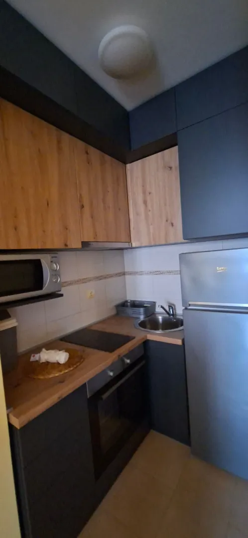 Small equipped kitchen with wooden elements and built-in appliances.
