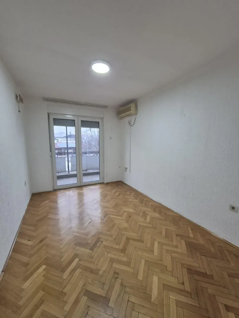Empty room with parquet flooring and access to a balcony.