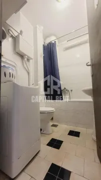 Small bathroom with a bathtub, toilet, washbasin, and washing machine. - image 7