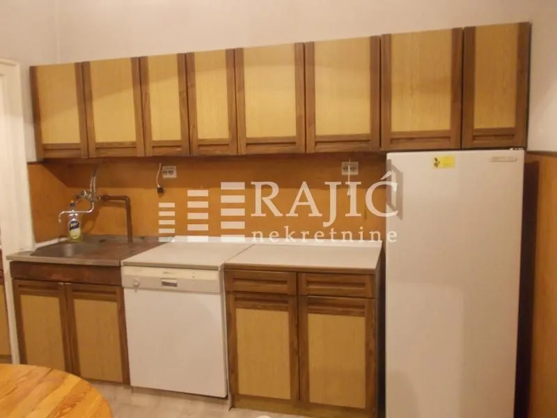 Smaller kitchen with wooden units and a refrigerator.
