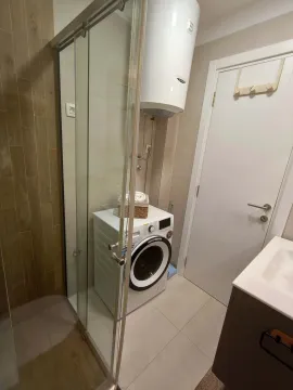 Bathroom with a shower cabin, washing machine, and water heater. - image 9