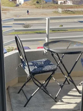 A balcony featuring a small table and chair with a view of the street. - image 6