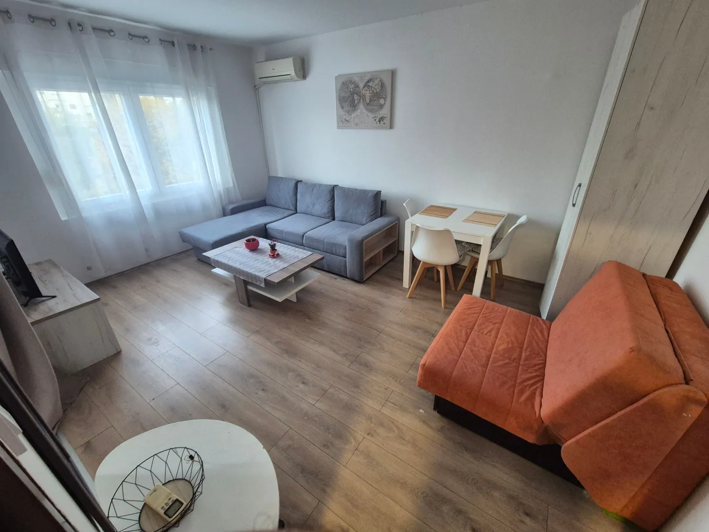 Living room with a sofa set, dining table, and air conditioning.