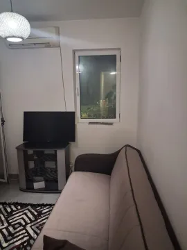 Smaller living room with a sofa, TV, and air conditioning unit. - image 6