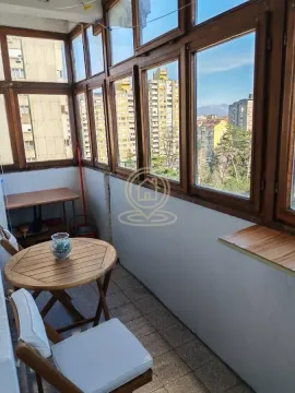 Enclosed balcony with wooden windows and sitting furniture. - image 7