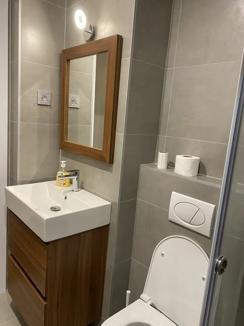 Moderno kupatilo sa drvenim namještajem, umivaonikom i ogledalom.