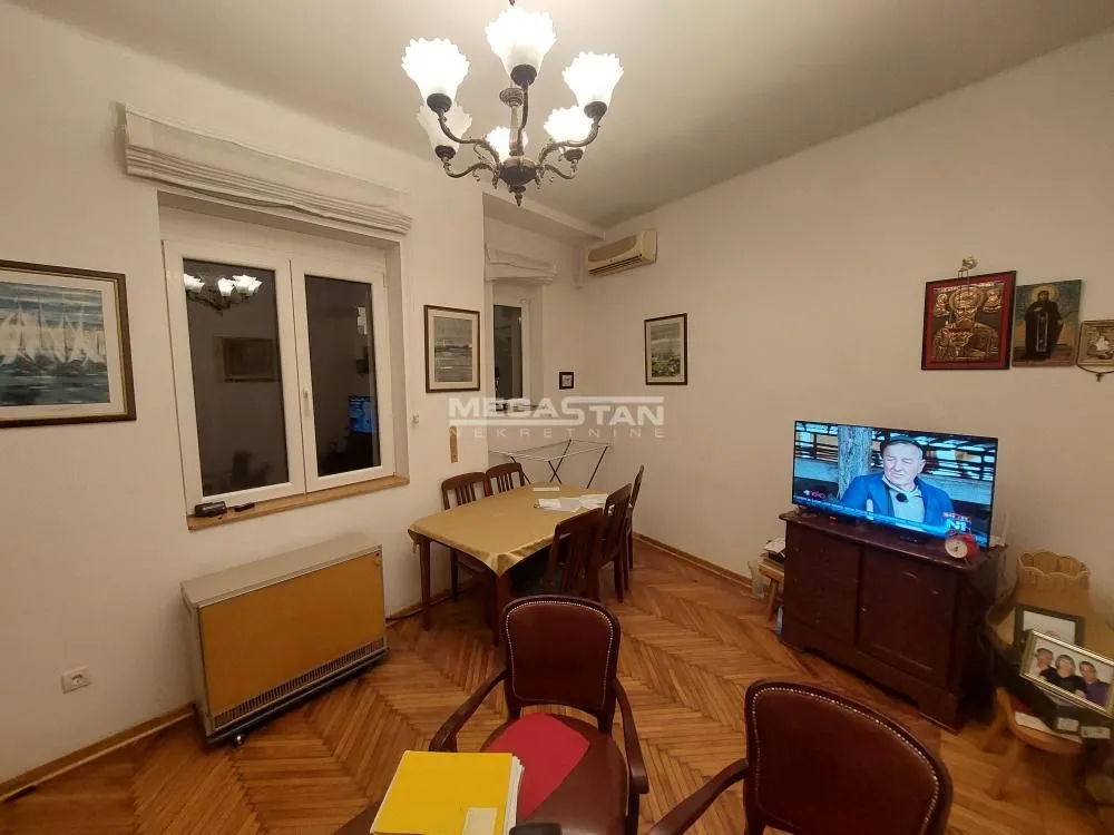 Living room with a dining table, television, and parquet flooring.