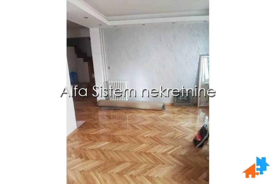 Prazna dnevna soba sa parketom i dekorativnim zidom.