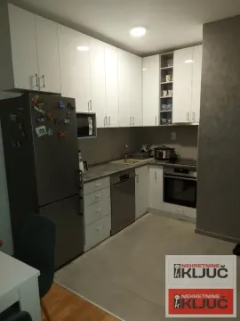 Manja opremljena kuhinja sa belim elementima i frižiderom. - image 3
