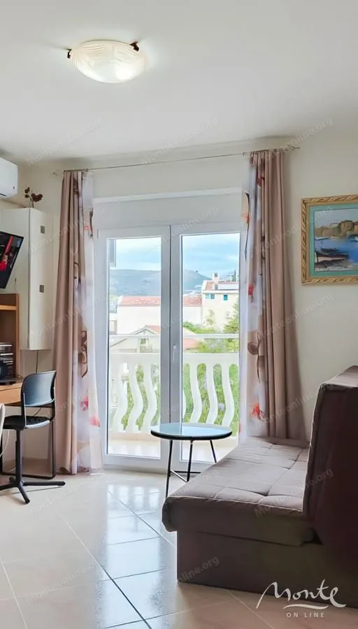 Dnevni boravak sa kaučem, radnim stolom i izlazom na terasu.