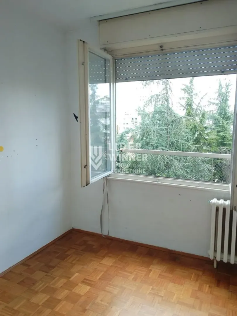 Empty room with parquet flooring and an open window.