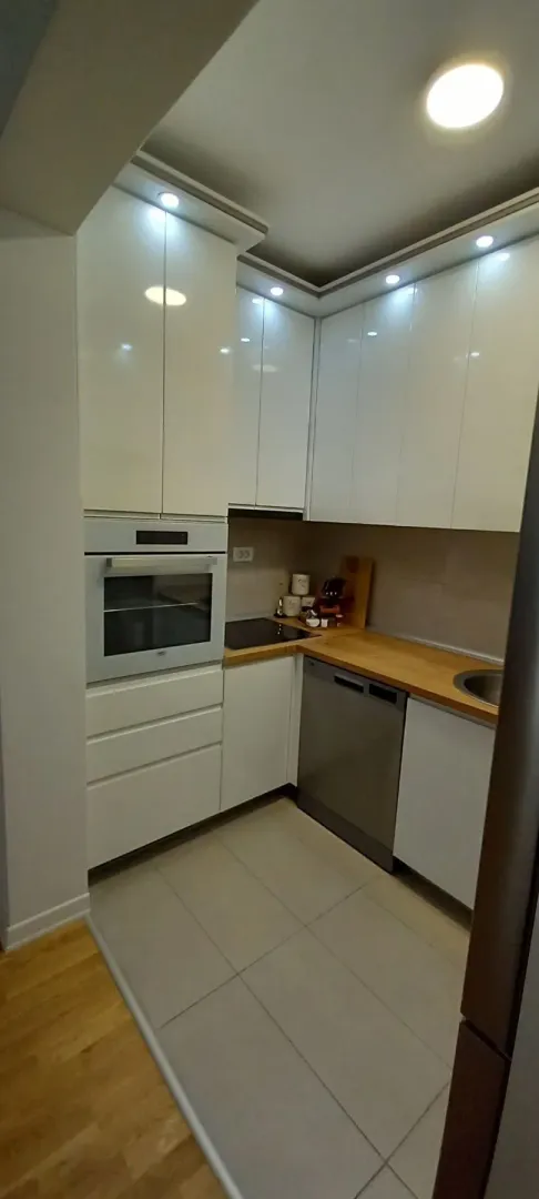 Modern white kitchen with a wooden countertop and built-in appliances.