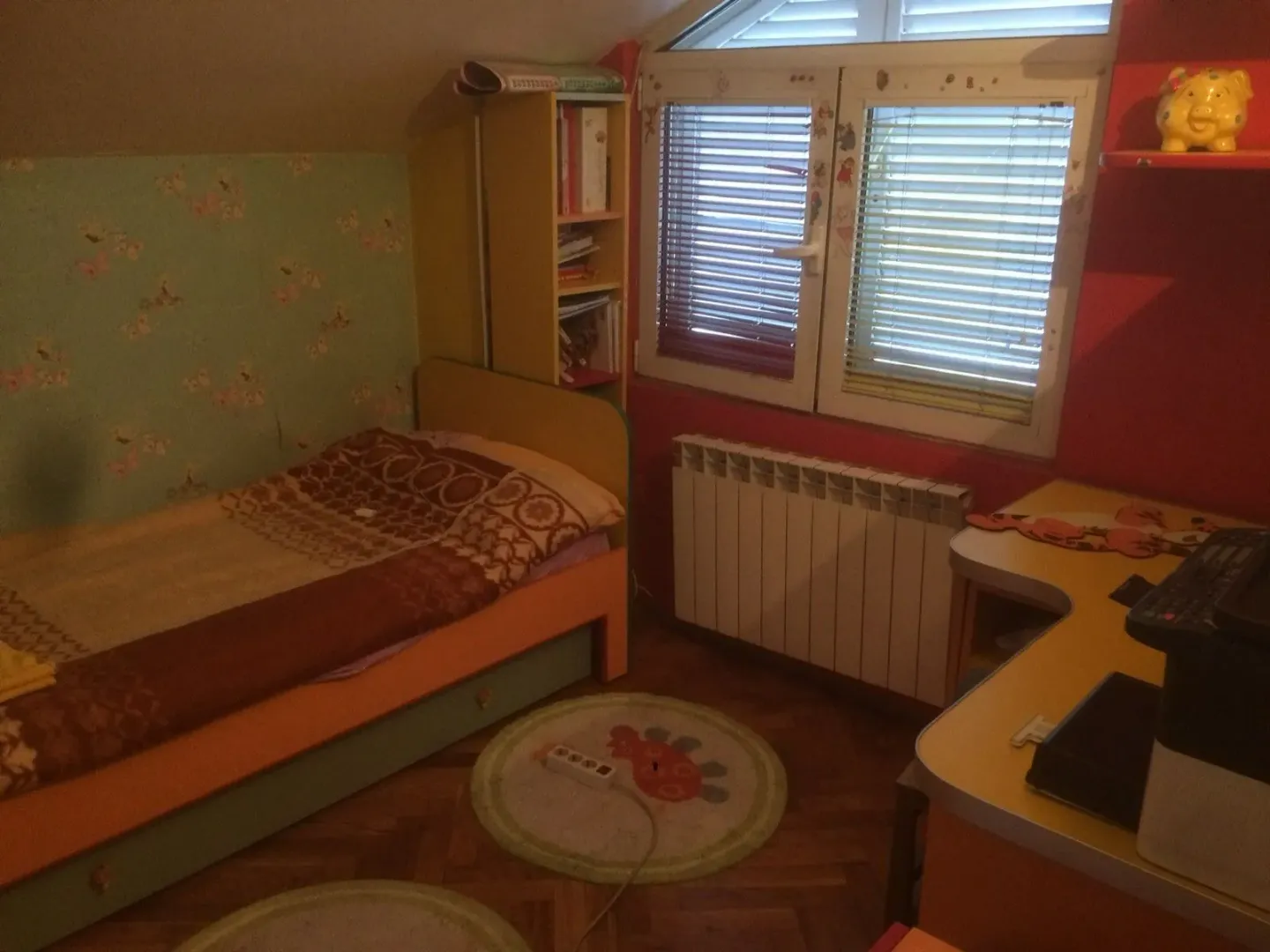 A children's bedroom featuring a single bed, a desk, and a window under a sloped ceiling.