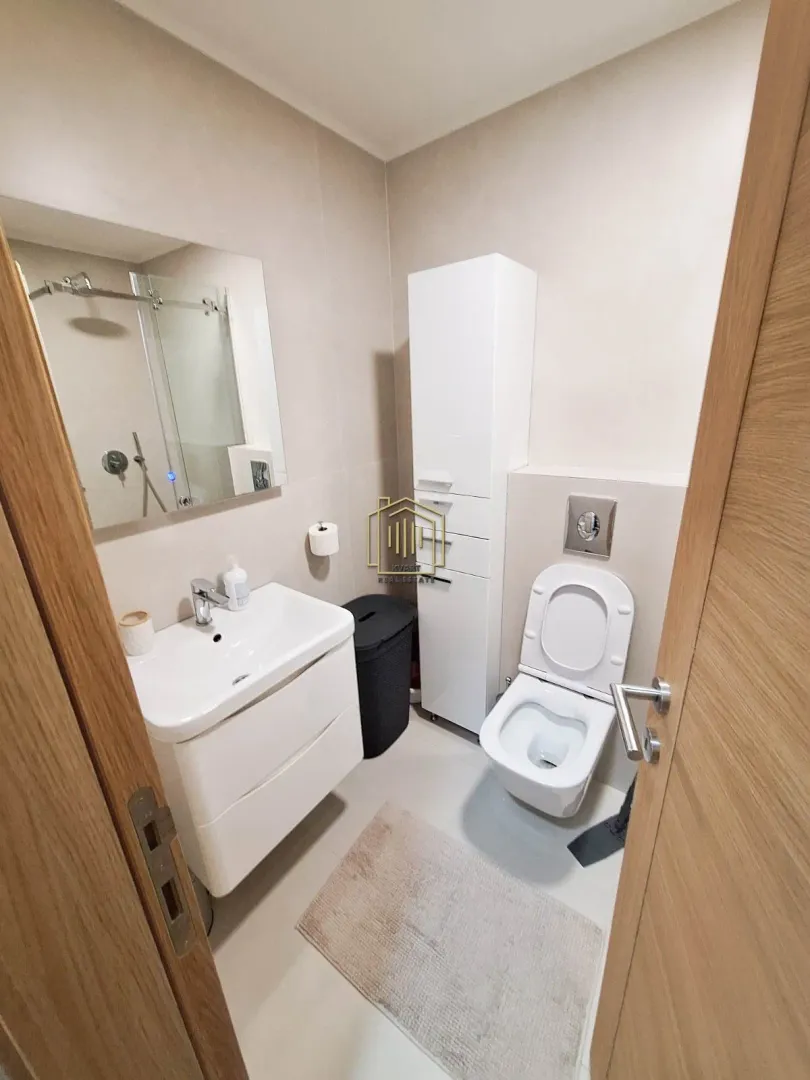 Modernly equipped bathroom with a washbasin, toilet, and walk-in shower.