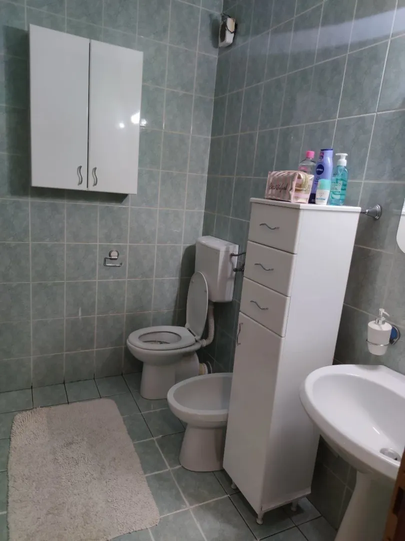 Kupatilo sa toaletom i bijelim namještajem.