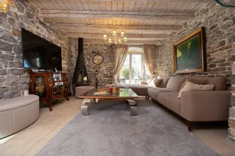 Living room with stone walls, wooden ceiling beams, and a fireplace. - image 13