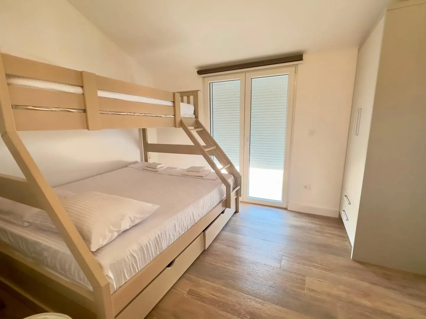 Bright bedroom with a bunk bed and balcony doors.