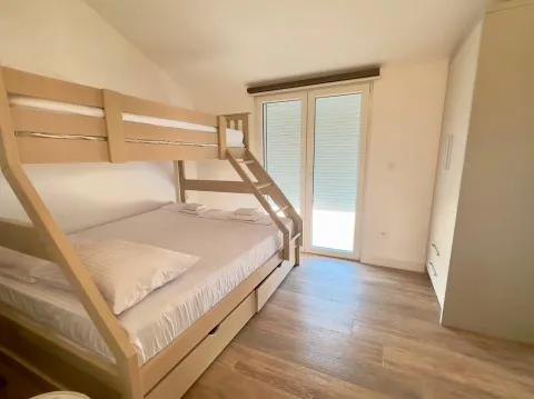 Bright bedroom with a bunk bed and balcony doors. - image 12