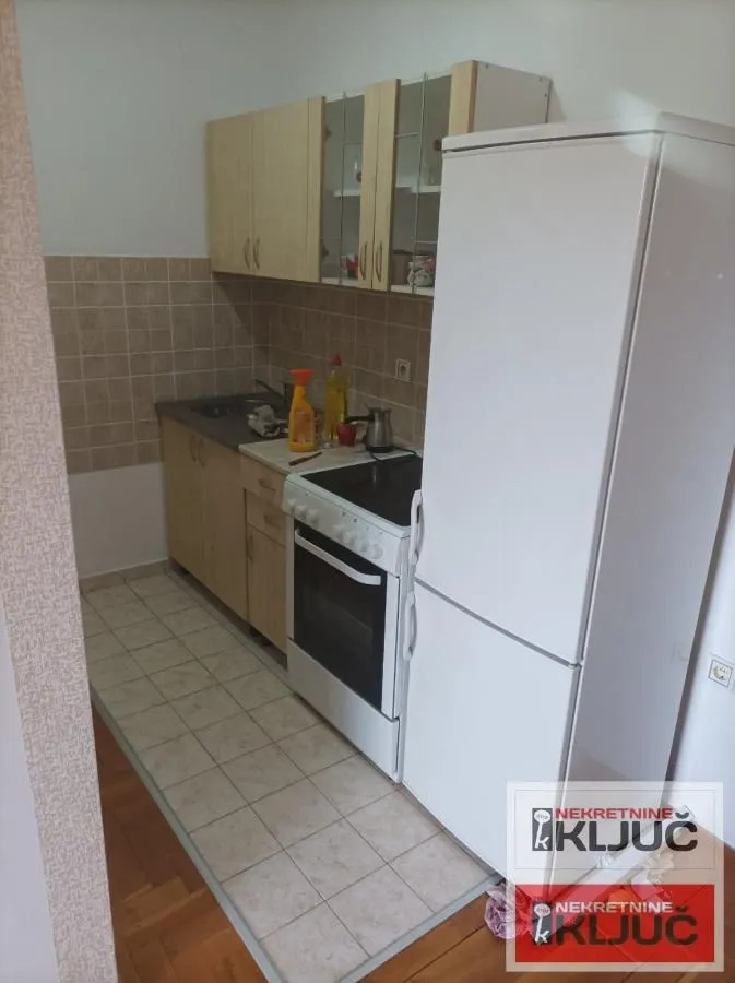 Manja kuhinja sa belim elementima i belim frižiderom.