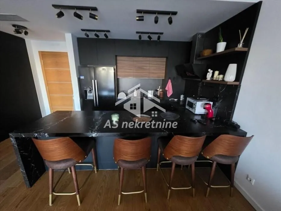 Modern black kitchen with a breakfast bar and bar stools.