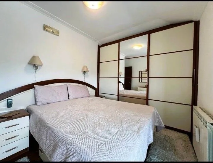 Namještena spavaća soba sa bračnim krevetom i velikim ormarom.