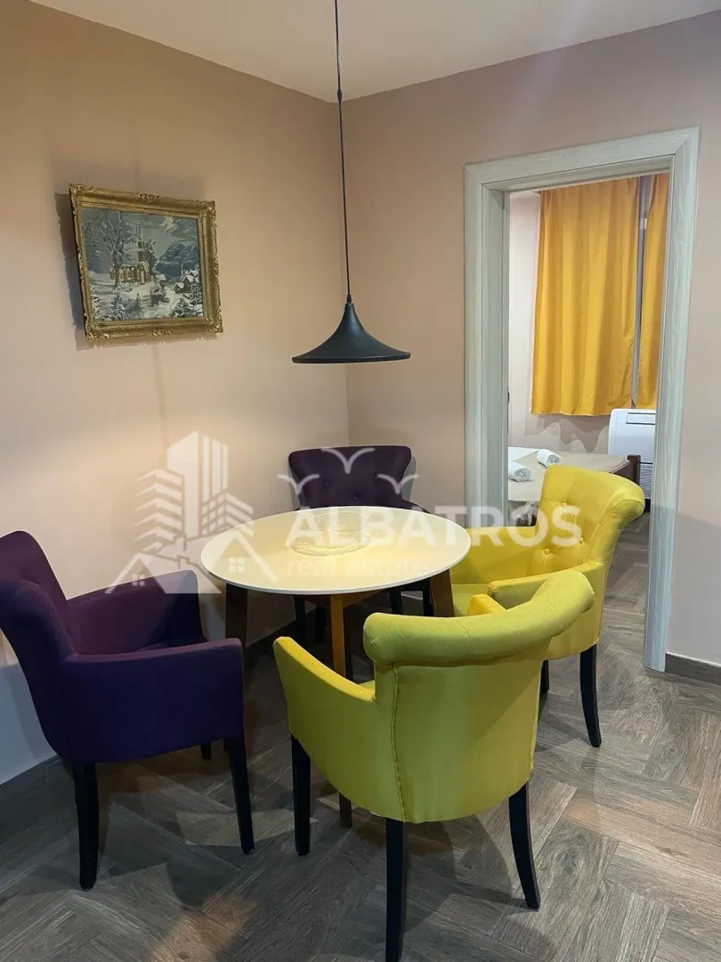 Dining area with a round table and colorful armchairs.