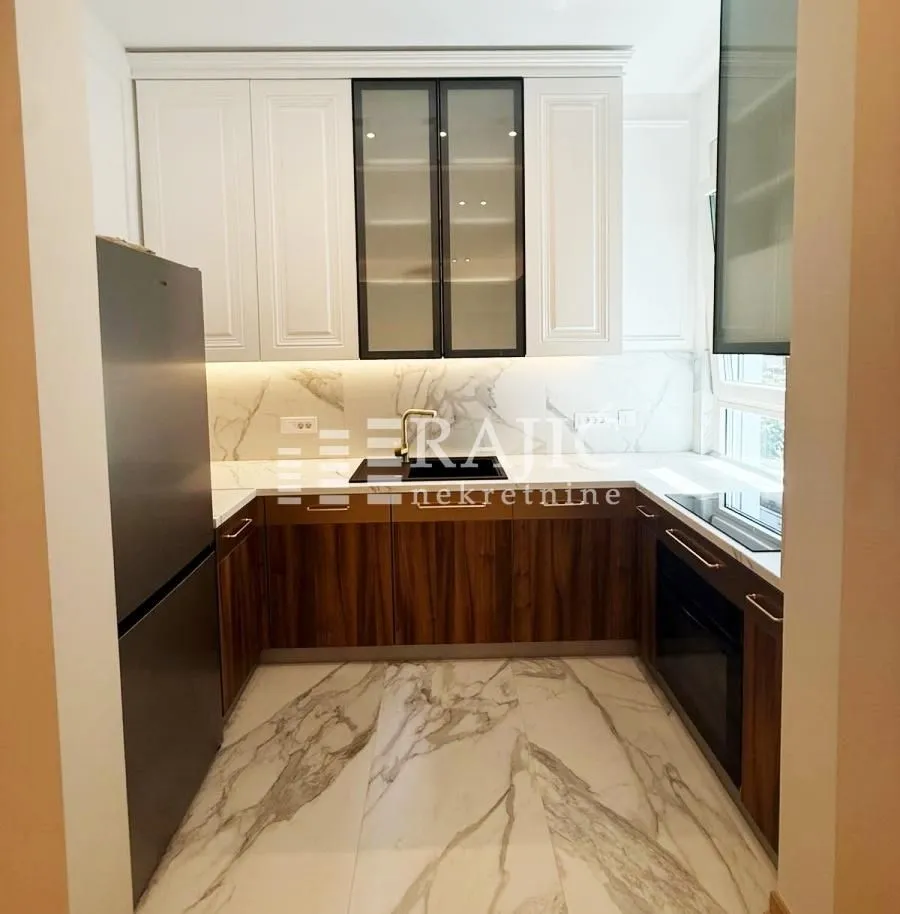 Modern kitchen with white upper cabinets, wooden lower cabinets, and marble-look tiles.