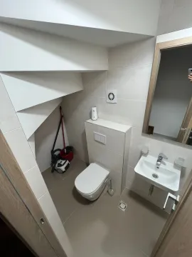 Manje kupatilo sa WC šoljom, umivaonikom i ogledalom ispod stepeništa. - image 9