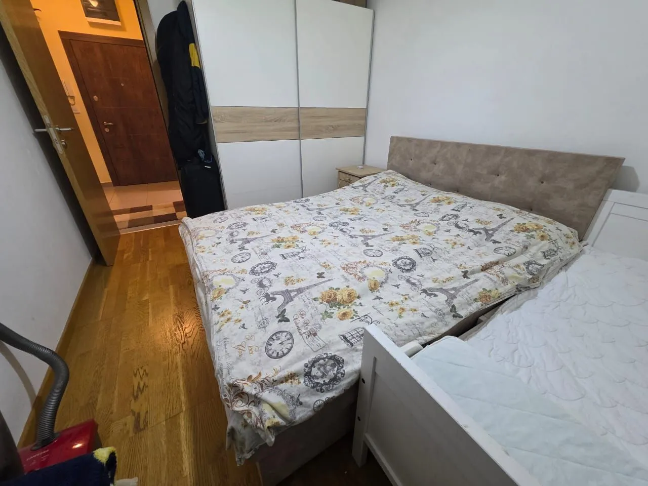Namještena spavaća soba sa bračnim krevetom, garderoberom i drvenim podom.