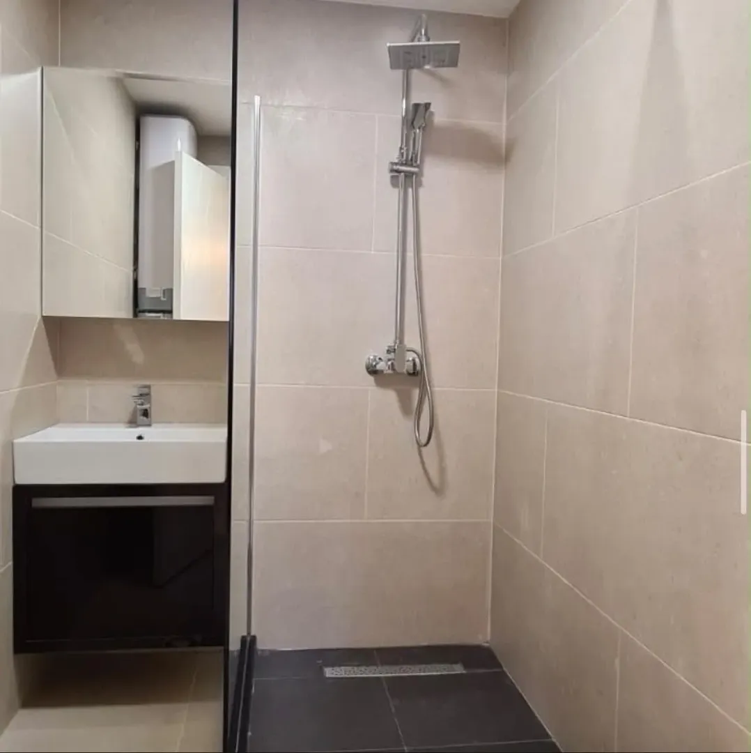 Savremeno opremljeno kupatilo sa tuš kabinom i umivaonikom.