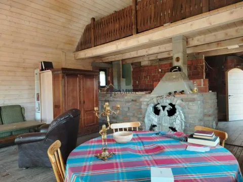 Unutrašnjost rustične drvene kuće sa trpezarijskim stolom i kaminom. - image 8