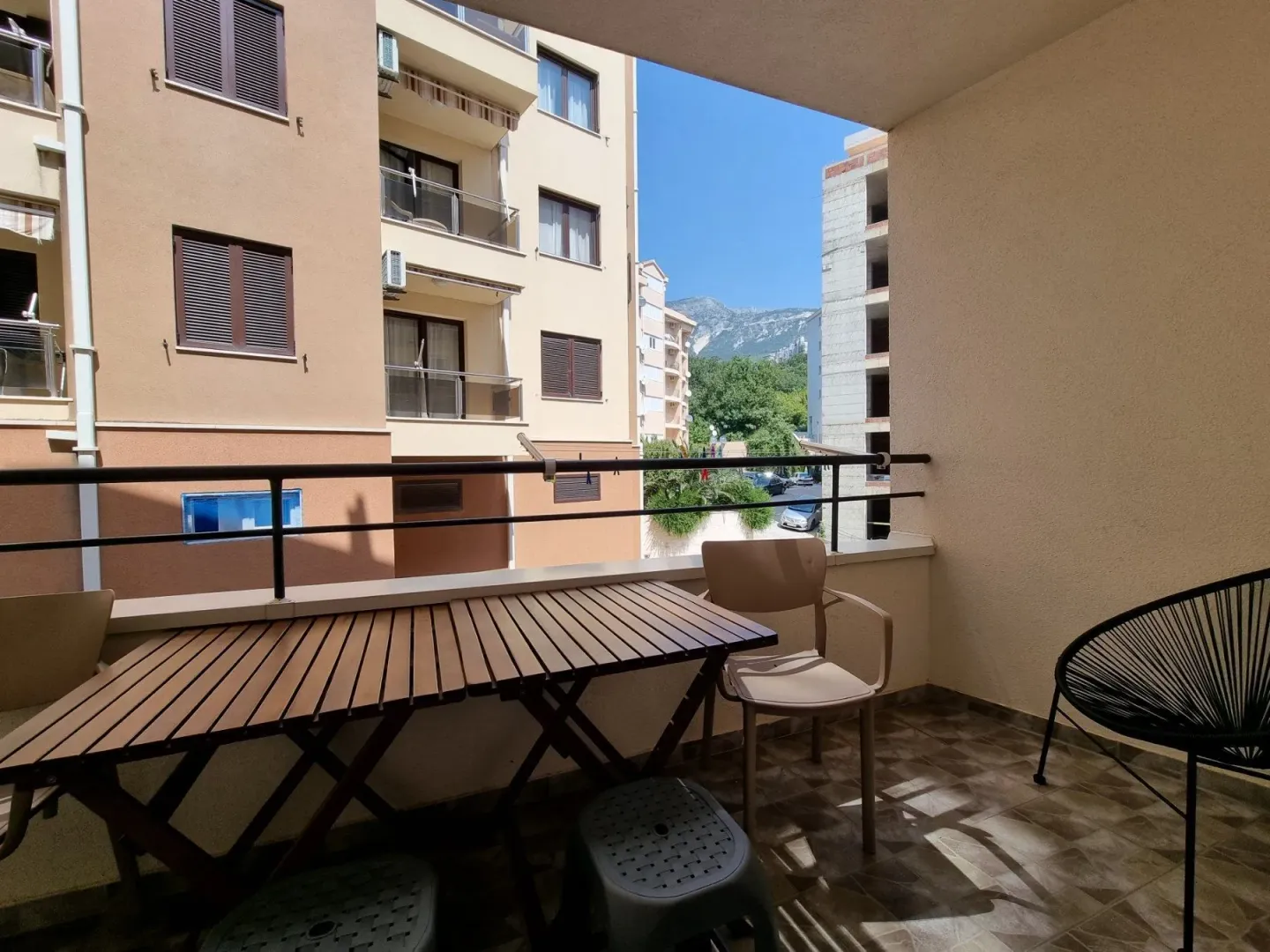 Namješten balkon sa stolom i stolicama i pogledom na naselje i planine.