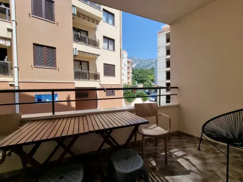 Namješten balkon sa stolom i stolicama i pogledom na naselje i planine. - image 6