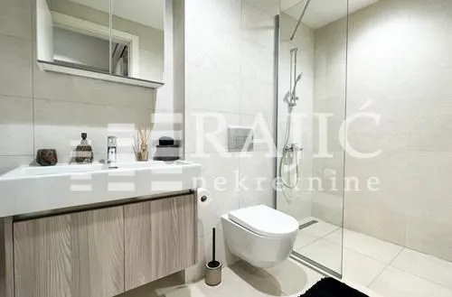Modern bathroom with a washbasin, walk-in shower, and a built-in toilet.