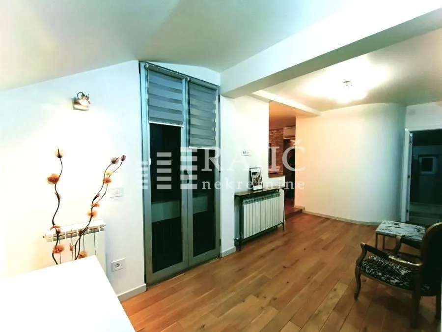 Living room with wooden flooring, balcony doors, and a passageway to another room.