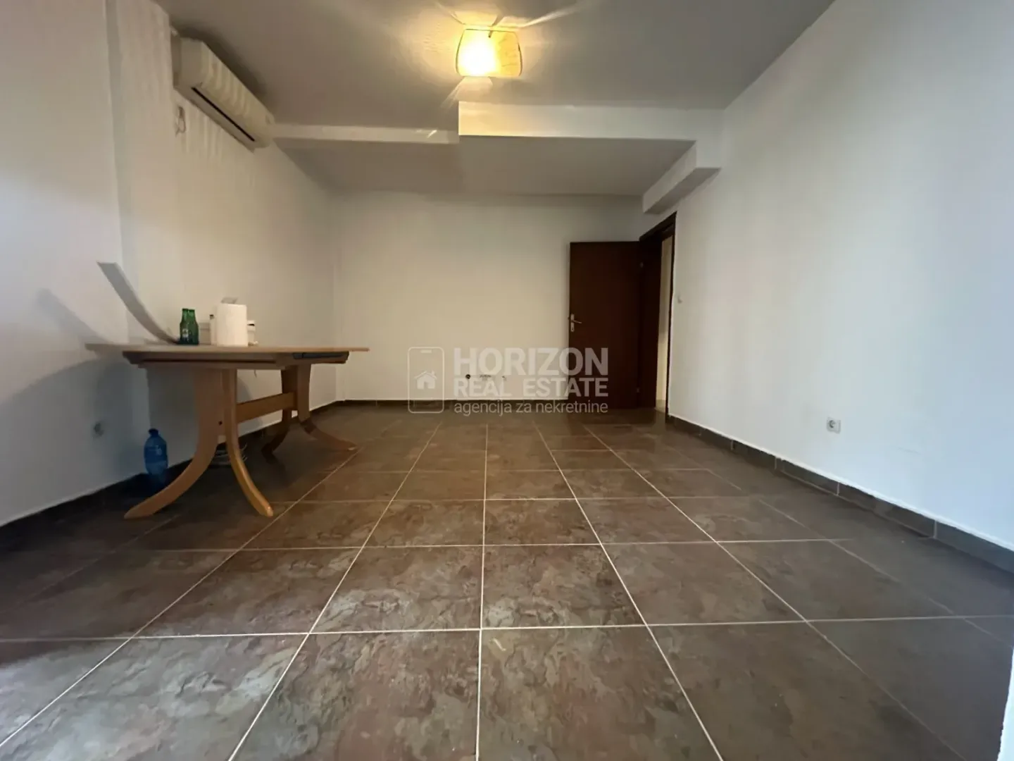 Empty room with ceramic floor tiles and a wooden table.