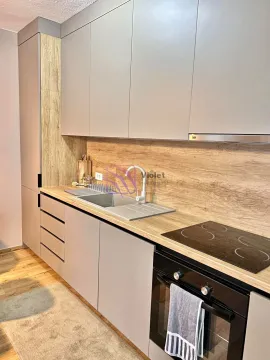 Moderna kuhinja sa sivim elementima i drvenom radnom površinom. - image 6
