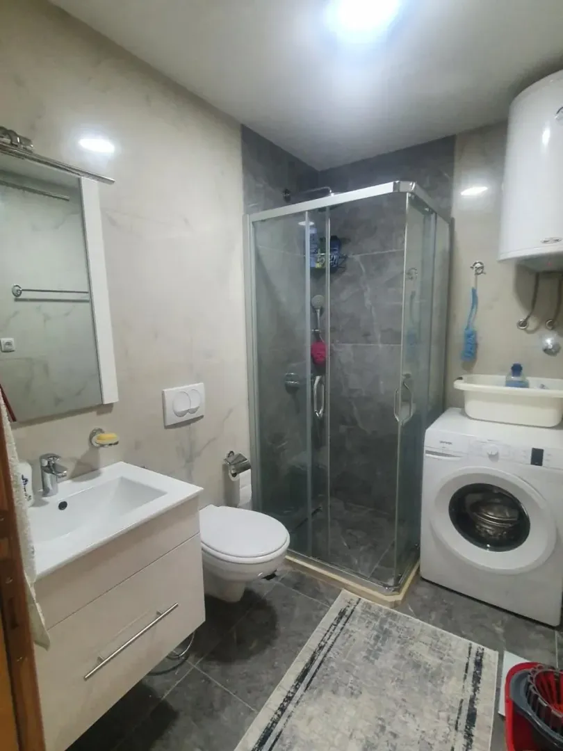 Bathroom equipped with a shower cabin, sink, toilet, and washing machine.
