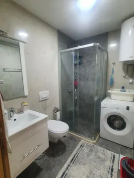 Bathroom equipped with a shower cabin, sink, toilet, and washing machine. - image 6