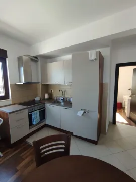 Small kitchen with beige cabinets and a dining table in the foreground. - image 5