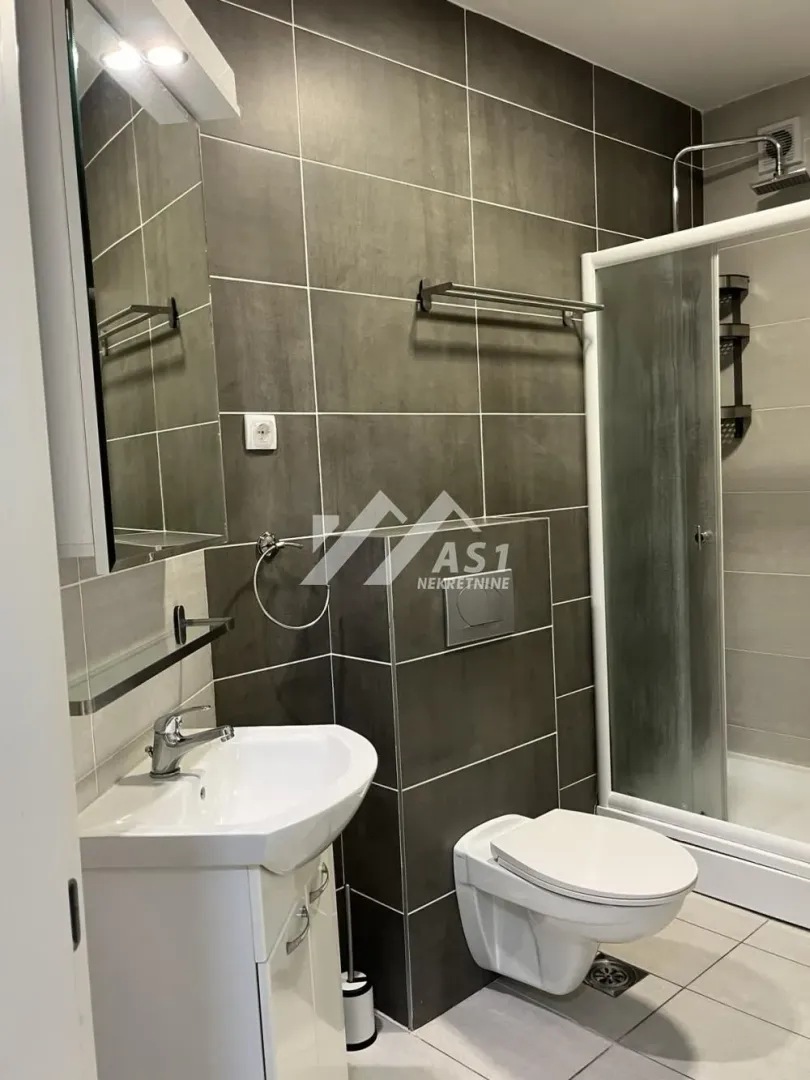Moderno kupatilo sa tuš kabinom, umivaonikom i wc šoljom.