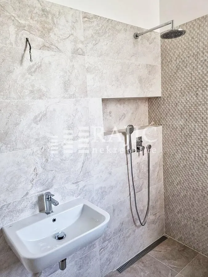 Modern bathroom with walk-in shower and washbasin.