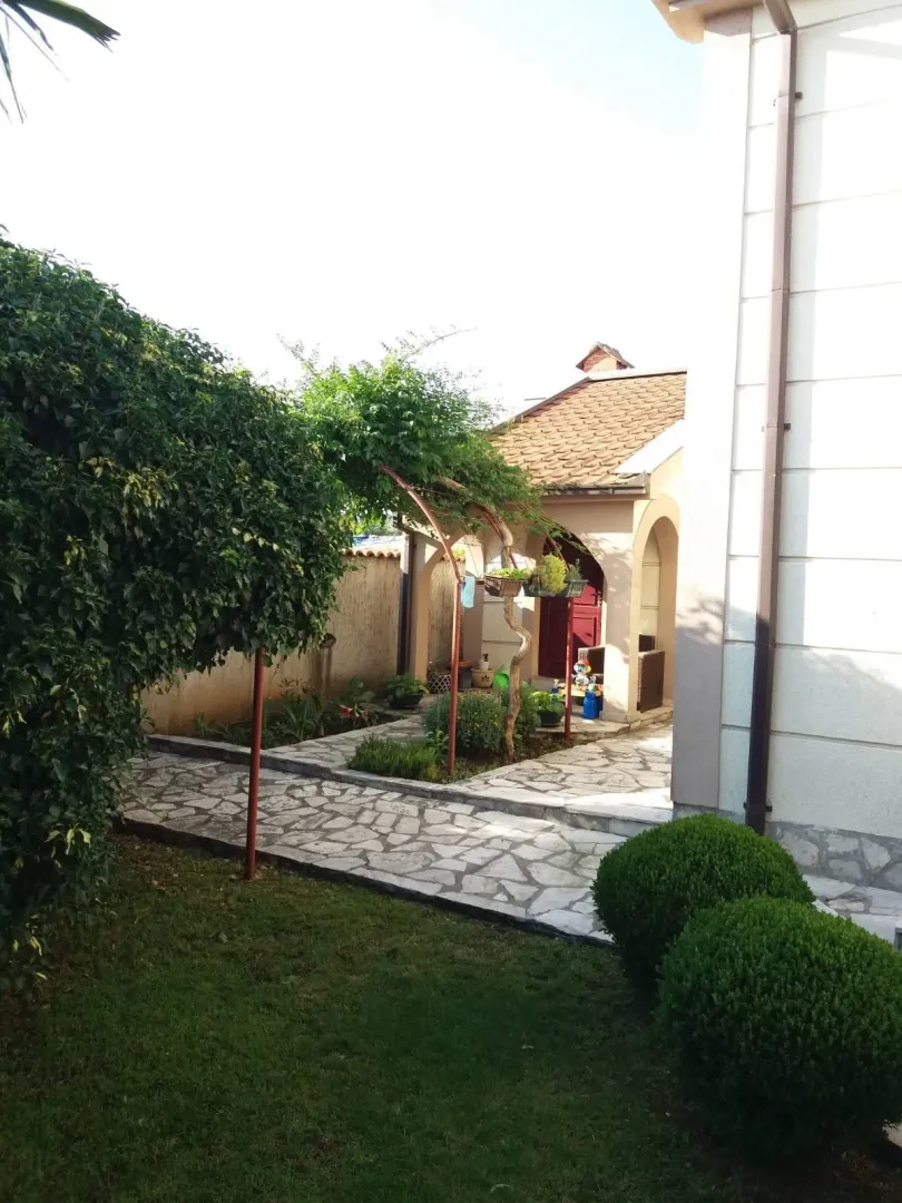 Landscaped yard with a stone pathway and greenery next to the house.