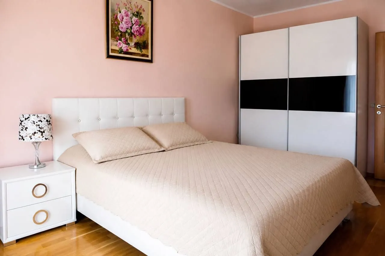 Furnished bedroom with a double bed, white wardrobe, and a nightstand.
