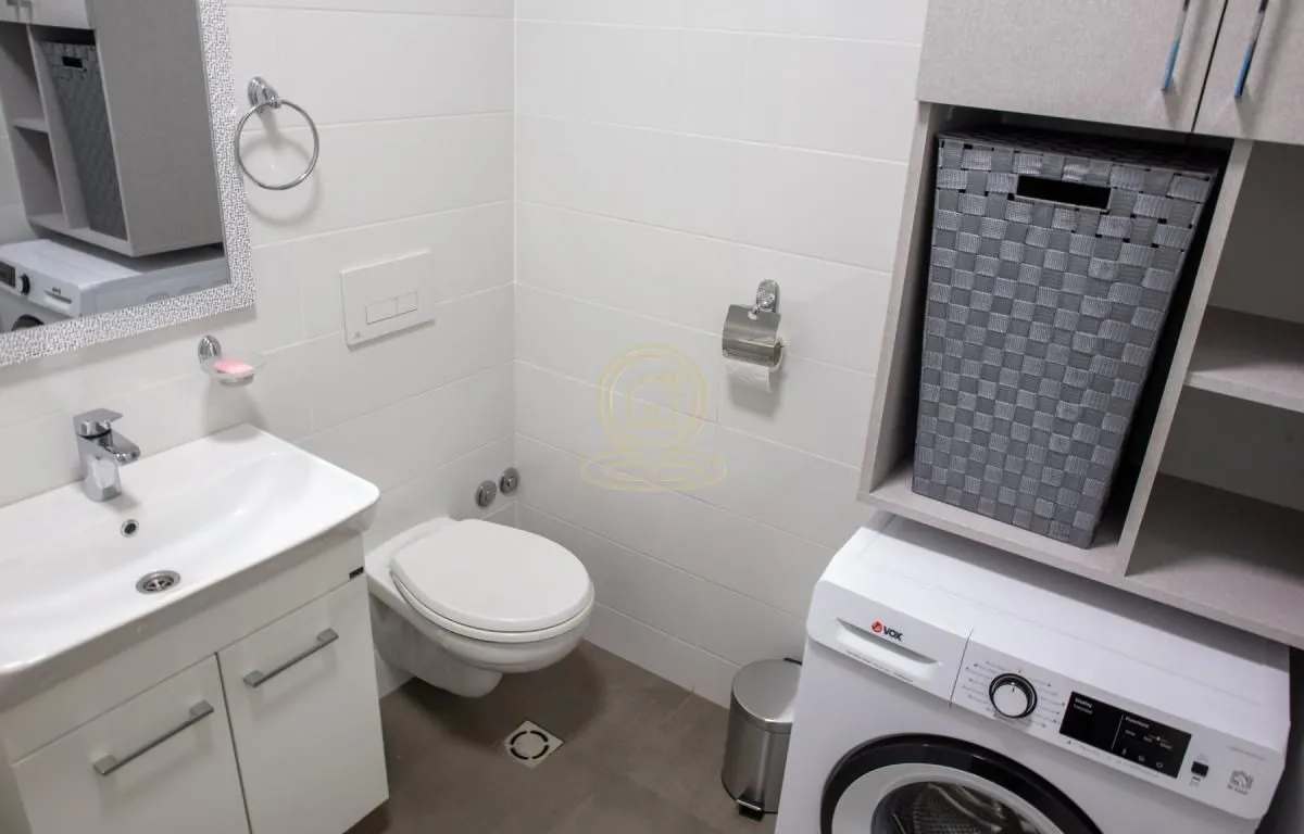 Moderno kupatilo sa umivaonikom, WC šoljom, mašinom za veš i elementima za odlaganje.