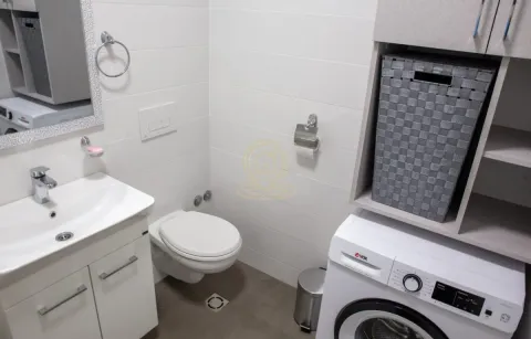 Moderno kupatilo sa umivaonikom, WC šoljom, mašinom za veš i elementima za odlaganje. - image 7