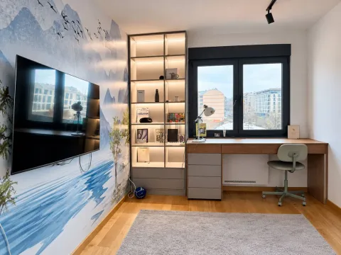Study room with a desk, shelving unit, and wall-mounted television. - image 5