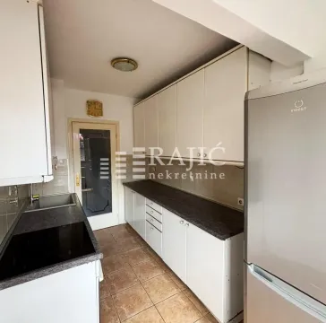 View of a small kitchen with white cabinets and a refrigerator. - image 8