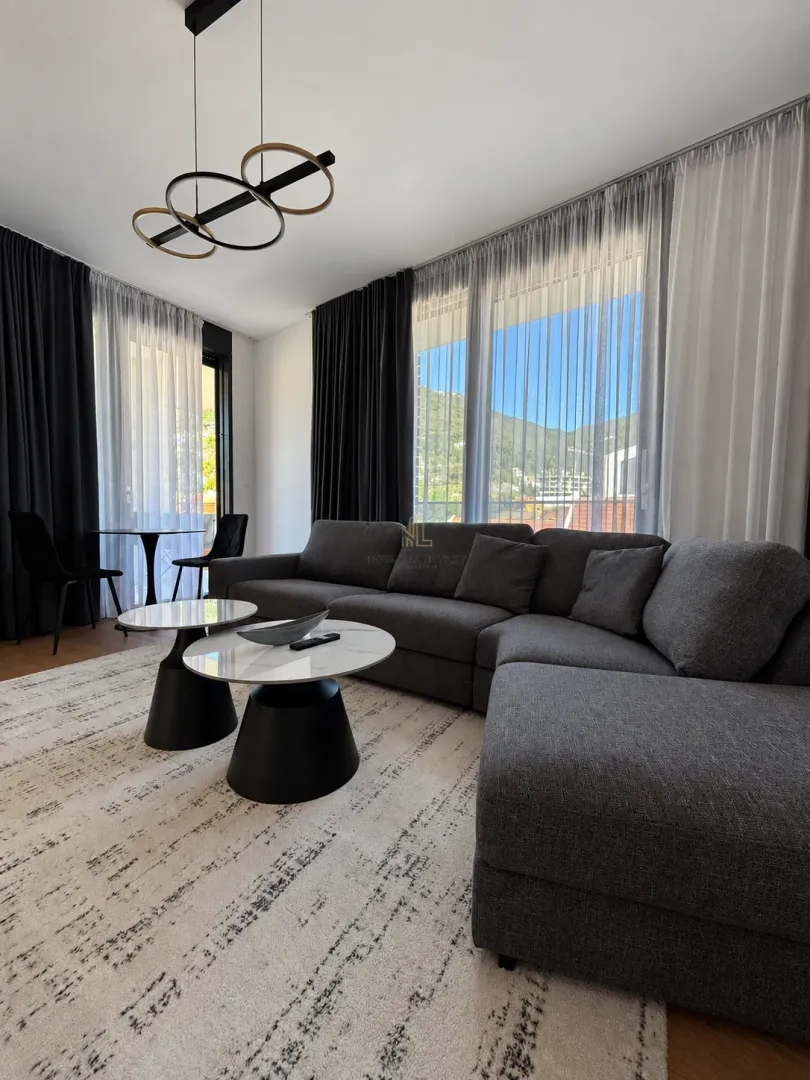 Modern living room with a large sectional sofa, coffee table, and large windows.